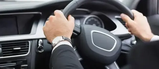 A man driving a car with both hands on the steering wheel.