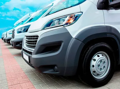 A lineup of white vans parked on a road.