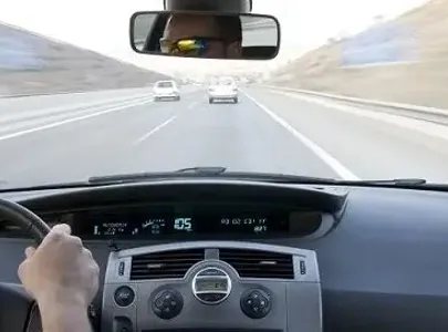 A person driving a car on the highway, focused and attentive, with other vehicles passing by.