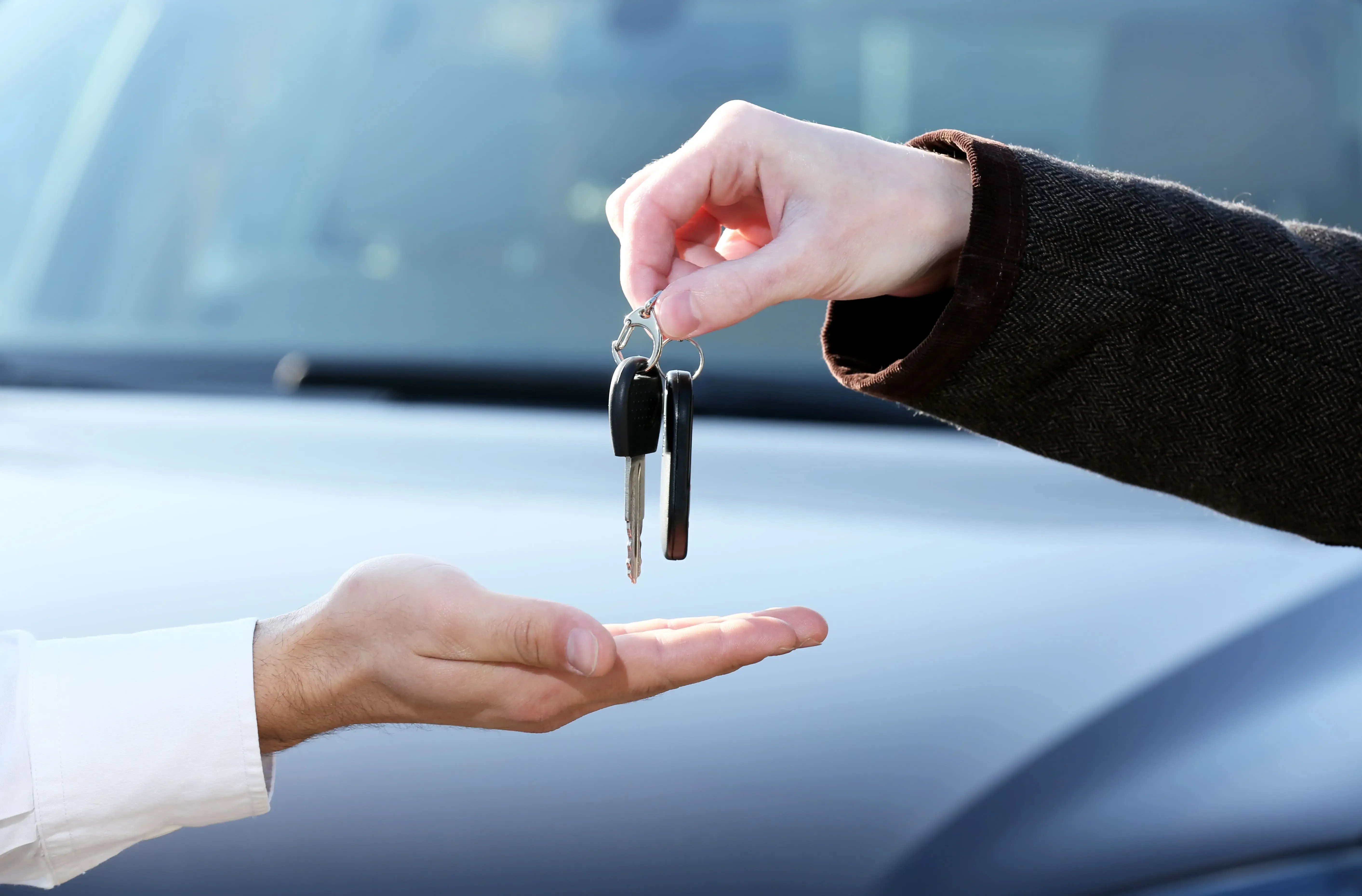 A person handing over a car key to another person.