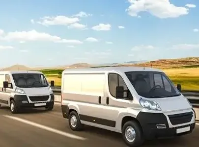 Three white delivery vans driving on the highway.