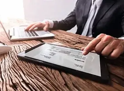 A professional man in a suit is engrossed in using a tablet computer for work purposes.