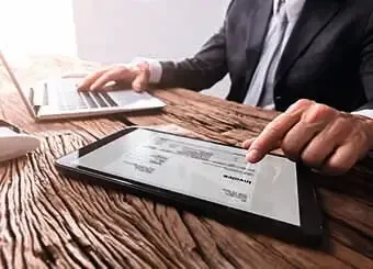 A professional man in a suit is engrossed in using a tablet computer for work purposes.